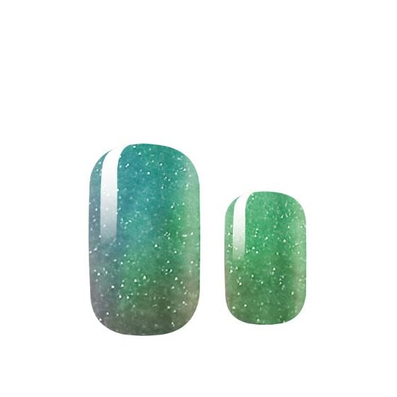 Two green glittery nail polish samples on a white background
